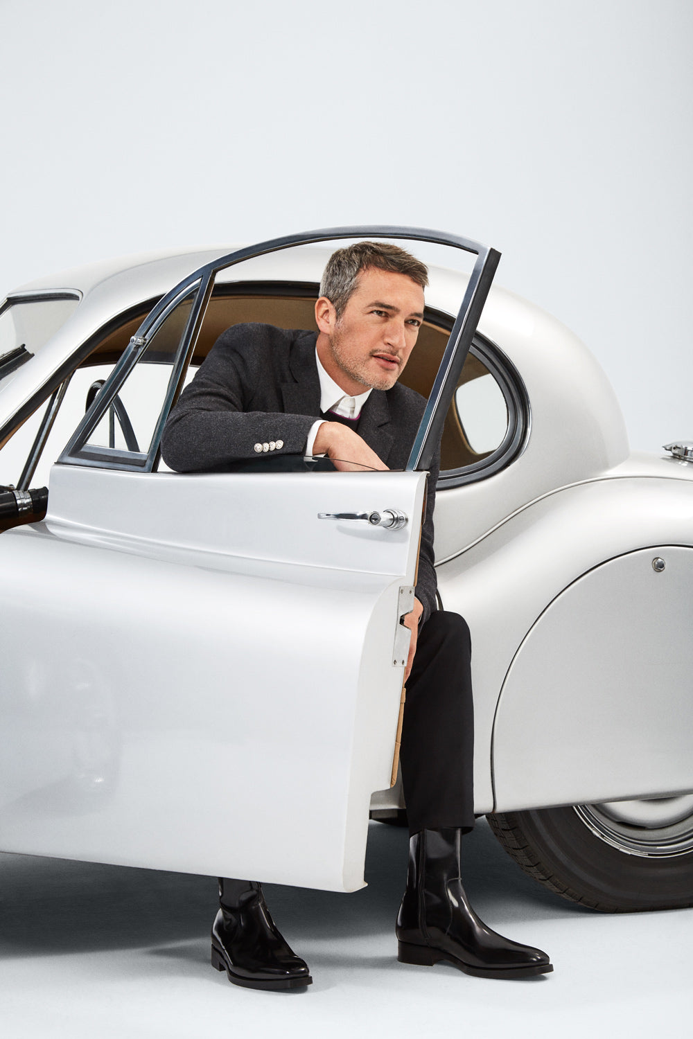 Modelo con traje blanco en un coche clásico