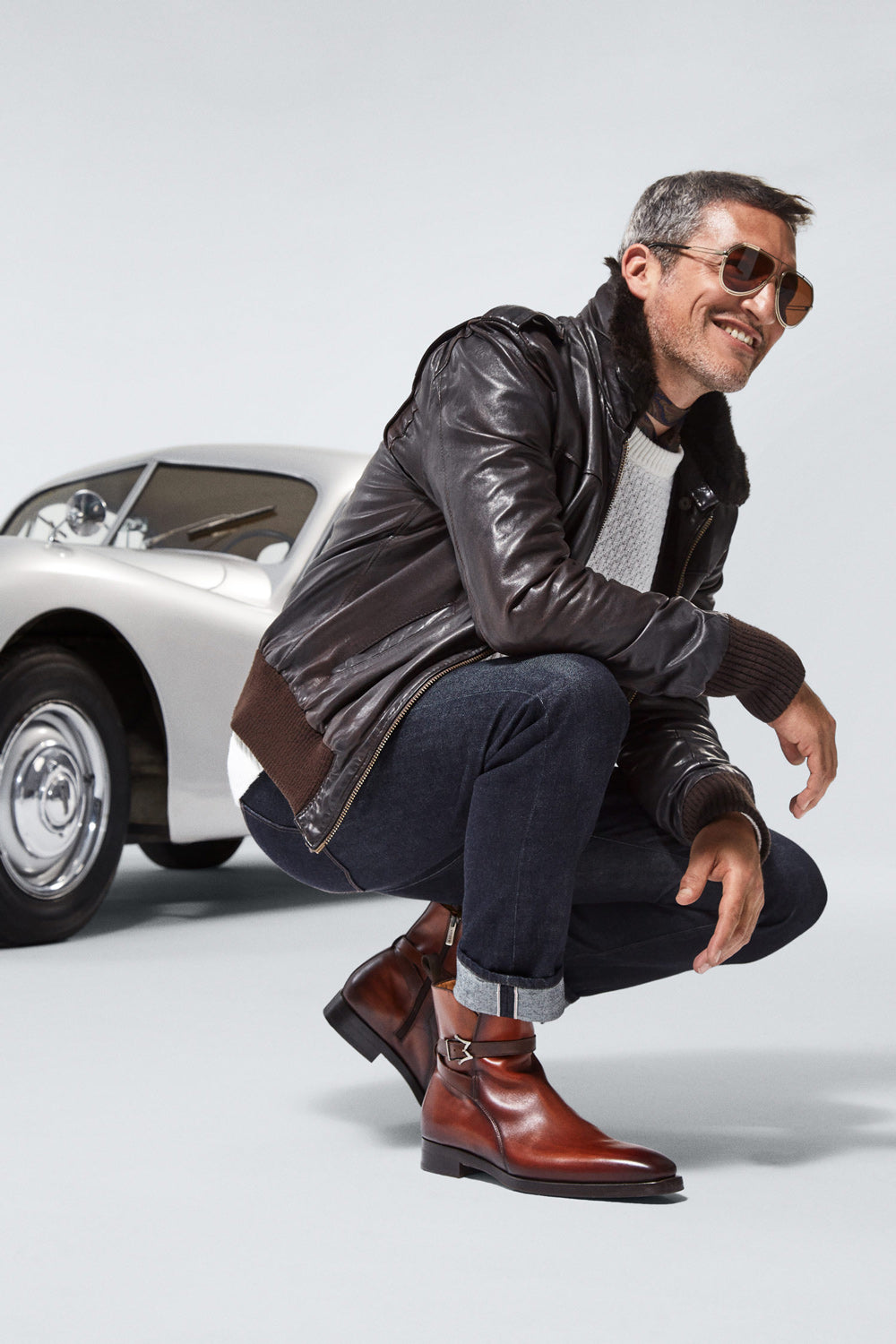 Modelo con zapatos marrones junto a un coche clásico